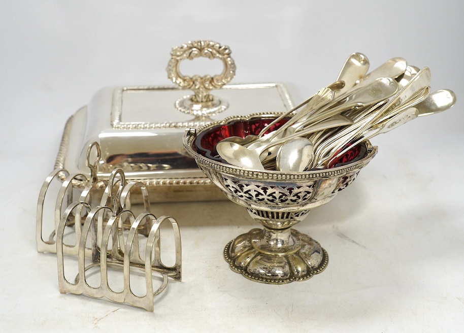 A quantity of plated flatware, four entrée dishes, two wine coasters, condiments, three toast racks etc., largest toast rack 16cm wide, 15cm high. Condition - good